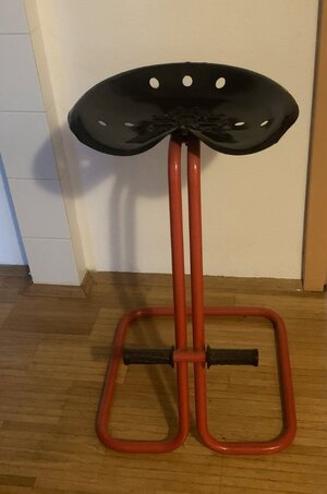 Hocker in Form eines Traktorsitzes mit rotem Gestell